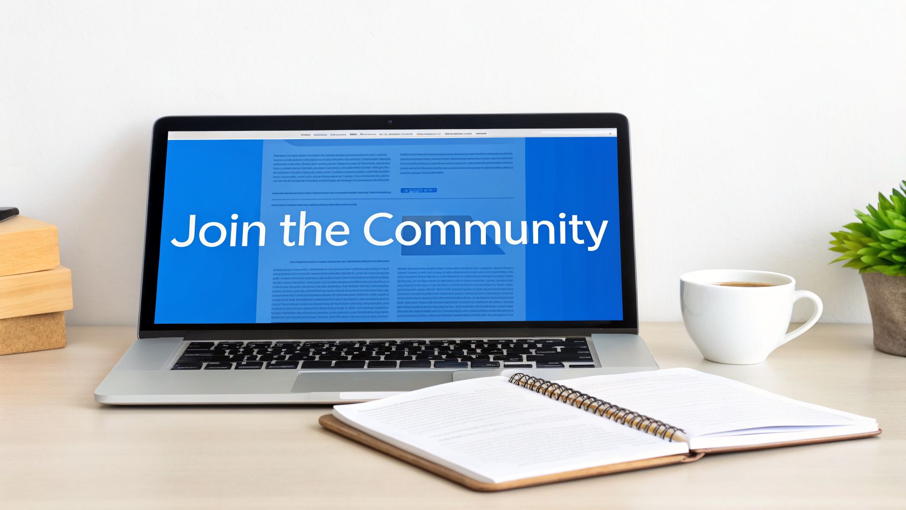 A laptop displaying 'Join the Community' on a blue screen sits on a desk with a notebook, coffee, and plant.
